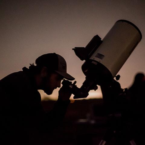 Astronomy student looks through telescope